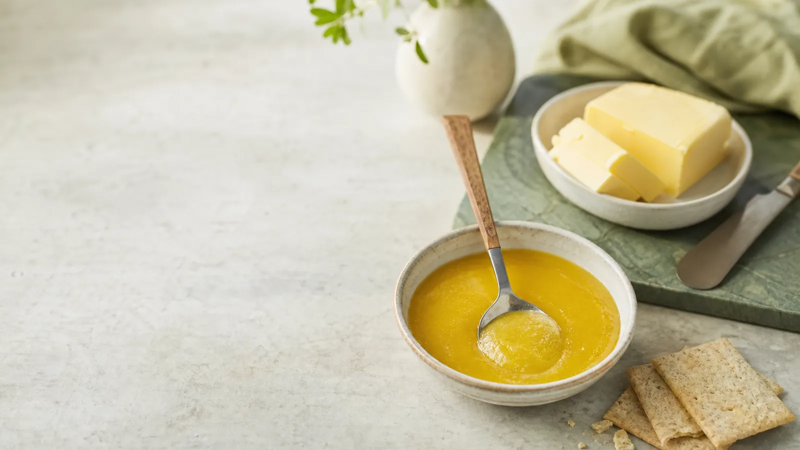Bowl of ghee beside butter and crackers on a kitchen counter